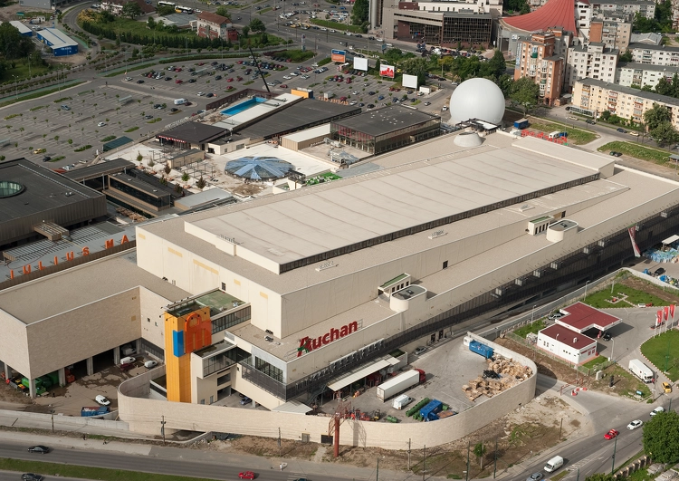 vue d'avion d'un supermarché Auchan couvert en membrane TPO, autour on peut voir le parking, des immeubles, la voirie.