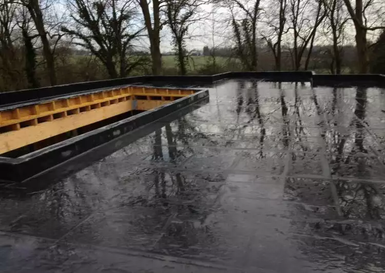 toiture en membrane EPDM collé sur panneaux OSB sur un chantier ossature bois sous la pluie