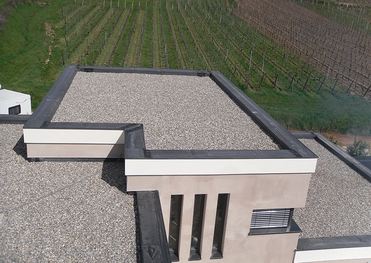 au premier plan toiture plate sur trois niveaux étanchéité EPDM lesté par des galets. Champ de vigne à l'arrière plan.