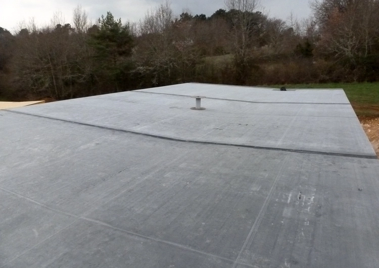 grande surface de toiture plate couverte en membrane EPDM dans une zone rurale, plusieurs bâches sont unies par des joints.